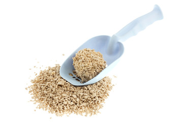 Plastic scoop for cleaning cat litter and a pile of filler on a