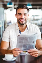  Young man having cup of coffee reading newspaper