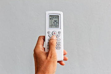 Left Hand holds a Remote Control of Air conditioner