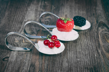 Dessert Spoon with berries on a wooden background