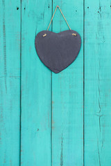 Blank slate heart hanging on antique teal blue door
