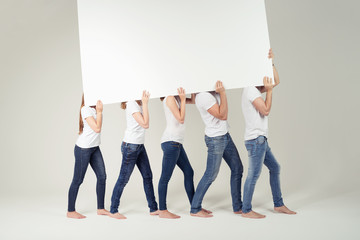 fünf leute tragen ein weißes plakat - obrazy, fototapety, plakaty