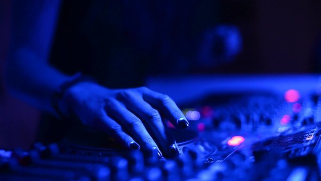 Girl DJ at work in the club/Hands of female Dj tweak various controls on dj's deck