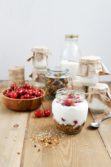 Yogurt in a jar with granola and cherry 
