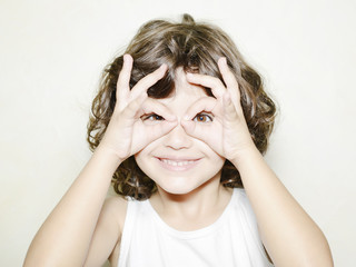 Niña mirando a través de unas gafas formada con sus manos