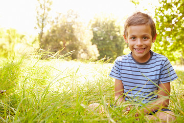 Portrait of a young boy sitting outdoors on a sunny day