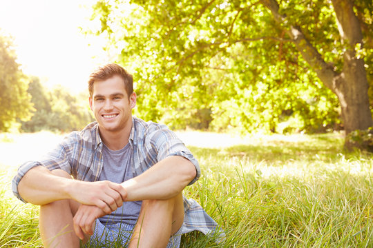 Young Man Sitting On Grass Relaxing