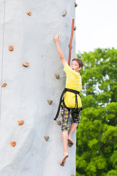 child wearing a harness climbing a rock climbing wall