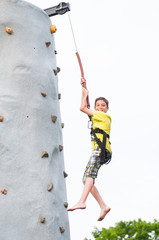 child wearing a harness climbing a rock climbing wall