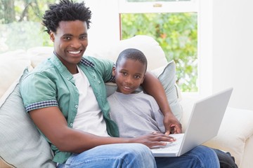 Fototapeta premium Father and son using laptop on the couch