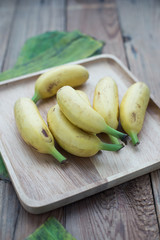 Golden bananas in the wooden plate with leaves