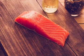 Pieces Salmon with herbs on wooden background.