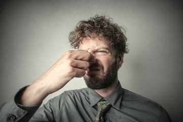 Disgusted man smelling a bad smell