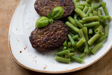 Close-up of grilled beef cutlets with beans, selective focus