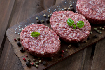 Raw beef cutlets with seasonings, rustic wooden setting