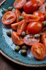 Close-up of cherry tomatoes with capers, salt and black pepper