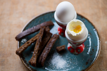 Close-up of soft-boiled eggs with breadsticks, selective focus