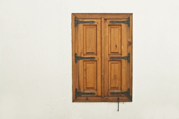 wooden window shutter with metal decoration on white wall