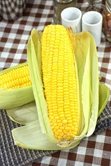 Sweet corn with green leaves on fabric background.