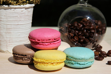 Colorful french macarons with coffee on the nature background
