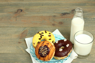 Donuts and glass of milk on wooden background