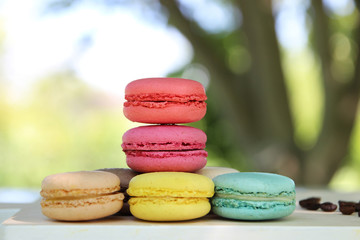 Colorful french macarons with coffee on the nature background