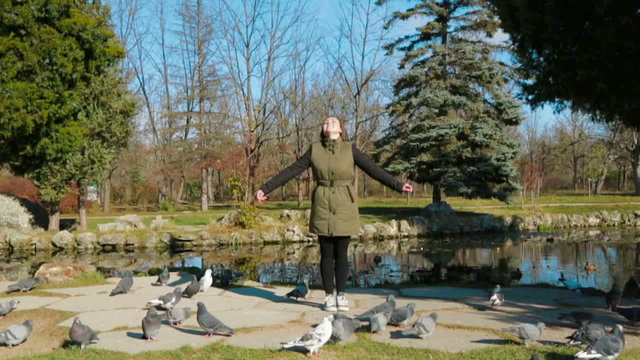 Cheerful Girl Standing In the Park Surrounded With Pigeons