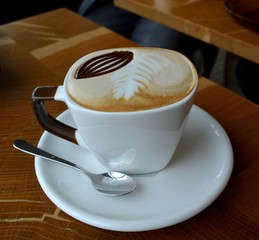Delicious cappuccino on a white cup on a wooden table