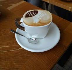 Delicious cappuccino on a white cup on a wooden table