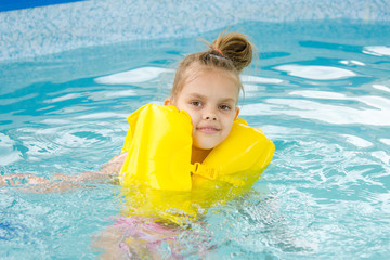 Girl swimming in the pool in the lifejacket