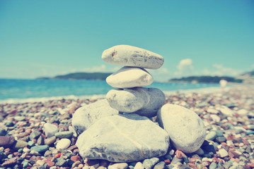 Stack of white stones balancing on the pebbly beach, on a sunny day. Image filtered in faded, washed out, retro style; summer vintage concept. - 86156292