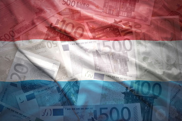 Obraz premium colorful waving luxembourg flag on a euro money background