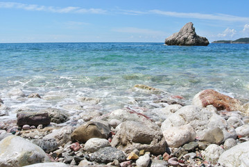 Summer coastal landscape - white rocky beach and turquoise sea, with waves crashing on the shore, on a sunny summer day.