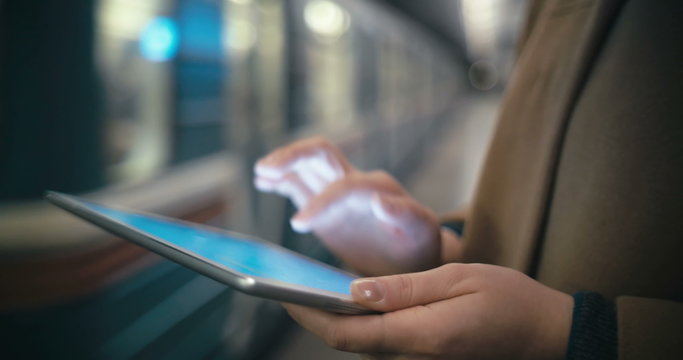 Woman using tablet PC by the leaving train in subway