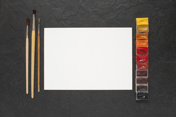 Sheet of paper and water colors on the table
