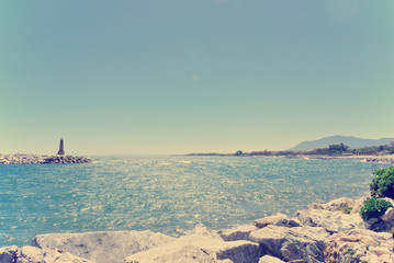 Rocky beach in Spanish luxurious seaside resort Puerto Banus, close to Marbella, on a sunny summer day. Filtered image in faded, washed-out, retro style; summer travel vintage concept. - 86158457