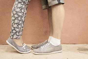 Closeup foot of kissing couple outdoor at street. Shod with same shoes of moccasins or sneakers. International or World Kissing Day 6 July or Valentine's Day