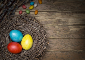 Easter eggs and bird nest on wooden background