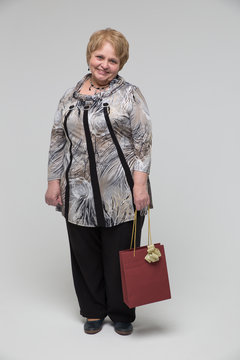 Portrait of an elderly happy woman on a grey background