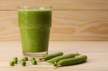  Smoothie with green peas  in a glass and pea pods  on wooden ta © patrikslezak