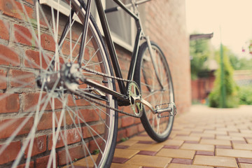 Old style singlespeed bicycle against brick wall, tinted photo