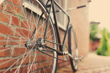 Old style singlespeed bicycle against brick wall, tinted photo