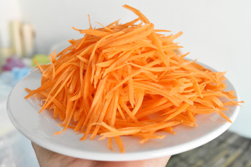 The orange carrot is cut into strips on dish