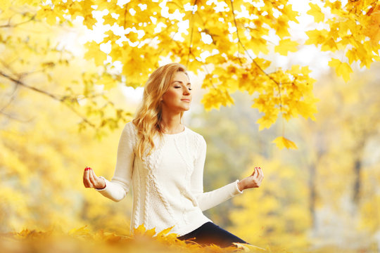 Woman meditating in autumn park