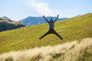 young adult man jumping on meadow