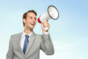 Young businessman in suit with a megaphone in his hand, smiling
