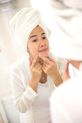 Young asian woman pressing her face, trying remove acne