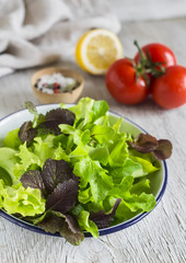 ingredients for salad - fresh lettuce, tomato and salad dressing on a light wooden background