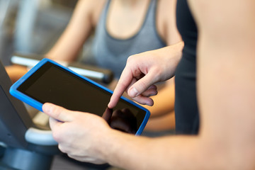 close up of trainer hands with tablet pc in gym