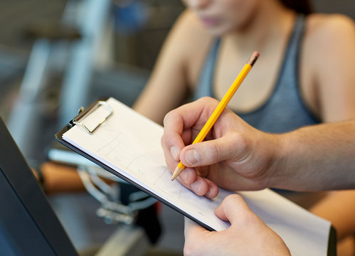 Close Up Of Trainer Hands With Clipboard In Gym